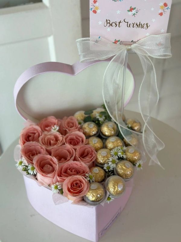 Heart-shaped box with roses and chocolates, topped with a 'Best wishes' card.