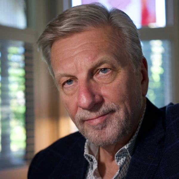 Mature man with gray hair and blue eyes in a cozy indoor setting.