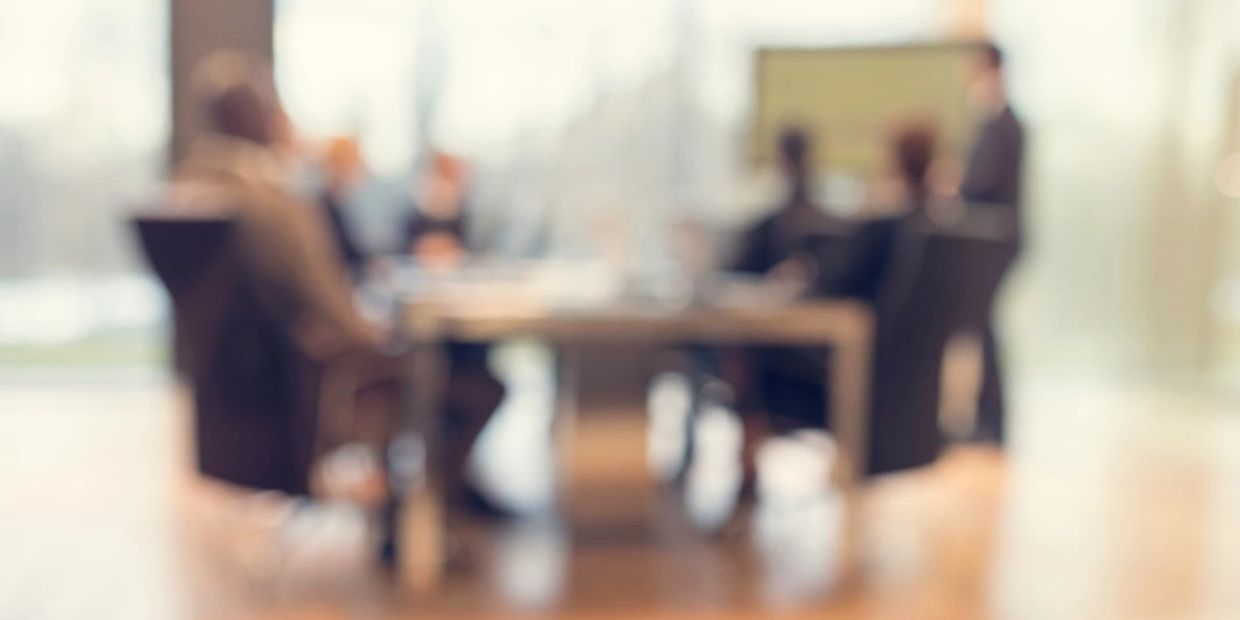 Blurry image of people in a business meeting.