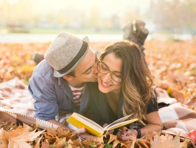 Couple amoureux lisant dehors couché dans les feuilles d'automne