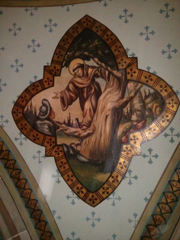 Religious fresco of a saint interacting near a tree, framed with decorative patterns.