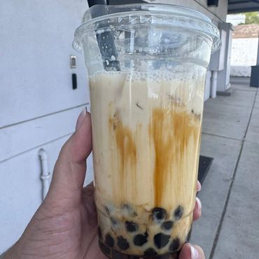 Hand holding a cup of bubble tea with tapioca pearls.