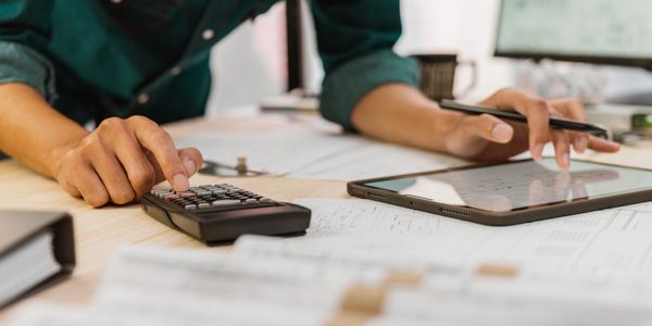 Man typing numbers into calculator while reviewing construction plans