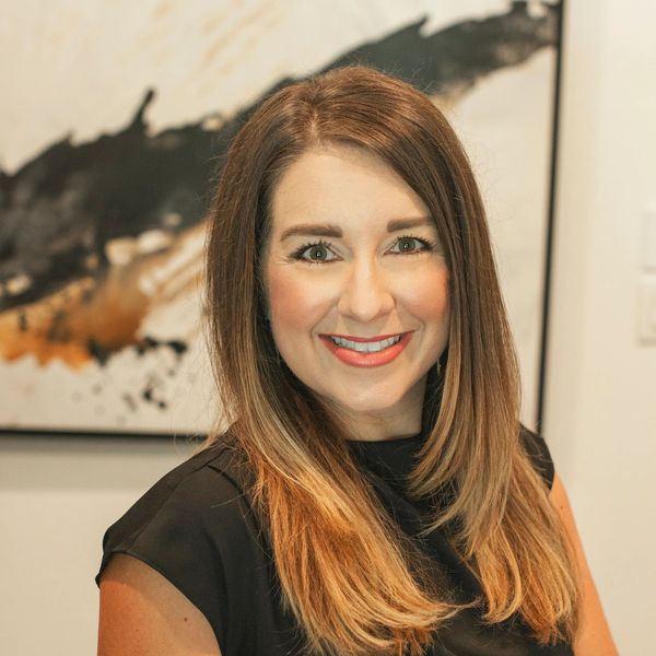 Smiling woman with long brown hair wearing a black top.