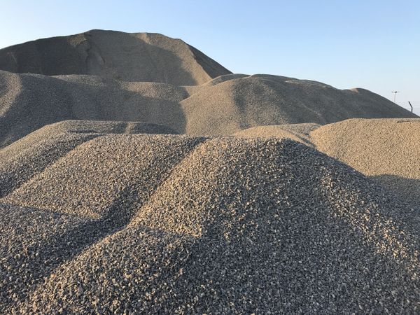 Large piles of gravel under a clear blue sky.