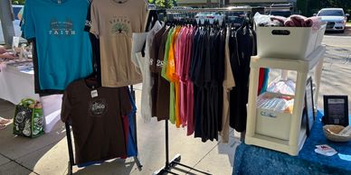 Colorful T-shirts displayed on racks at an outdoor market stall.