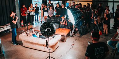 A group gathered around a couch for a photoshoot or interview setup.