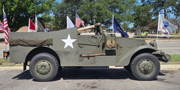 Military vehicle with US flags in the background.