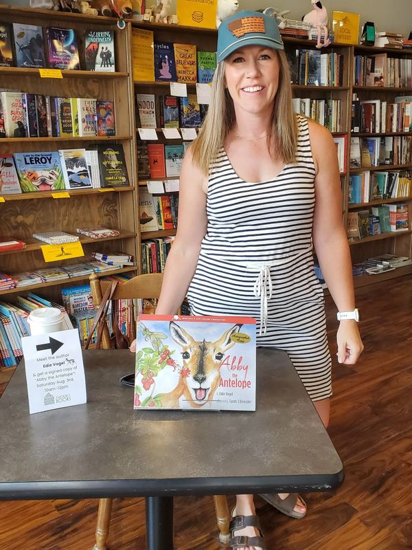 Author standing behind a table with her book in a bookstore.
