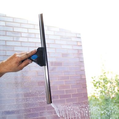 Hand cleaning a window with a squeegee.