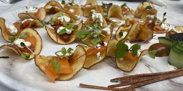 Gourmet chips with salmon, cream, and herbs on a marble plate.