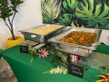 Buffet setup with pasta salad and curry shrimp dishes.