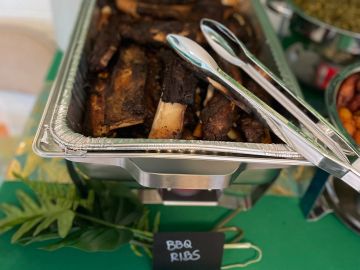 Tray of BBQ ribs with tongs.