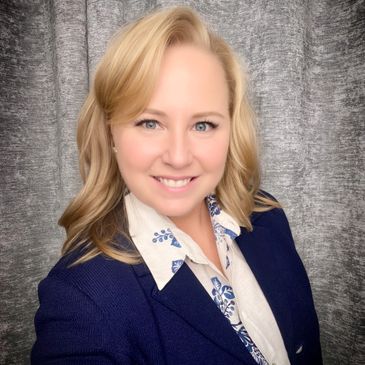 Smiling woman in business attire posing against a gray backdrop.