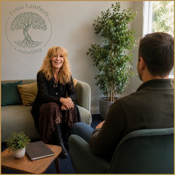 A female counselor talks with a male client in a cozy office setting.