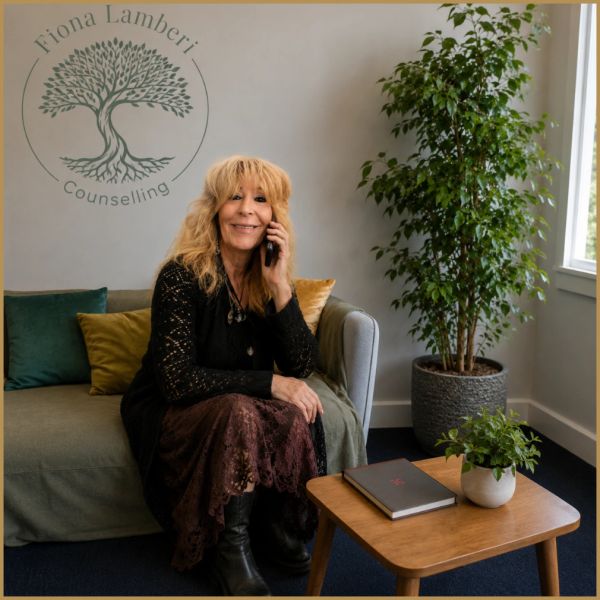 Woman sitting on a couch, talking on the phone in a counseling office.