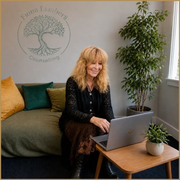 A woman working on a laptop in a cozy counselling office with plants.
