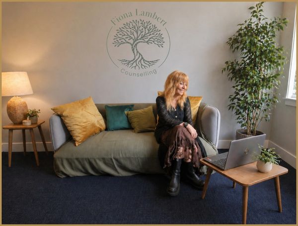 Fiona Lambert, person-centred counsellor, sitting on a sofa with laptop, online counselling session
