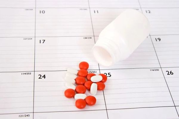 Red and white pills spilled from a bottle on a calendar.
