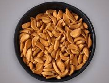 Black bowl filled with shelled peanuts on a gray surface.