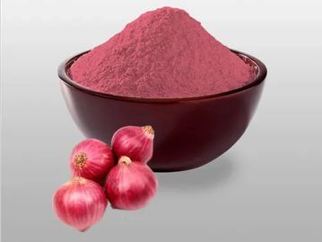 A bowl of red onion powder with fresh red onions beside it.