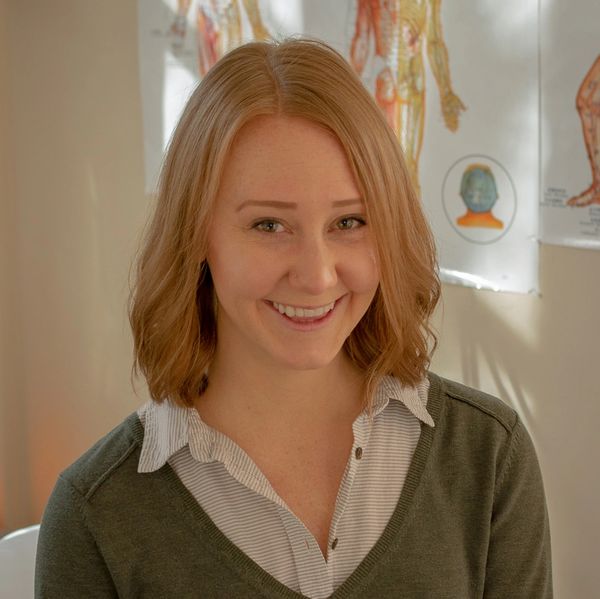 Smiling woman with shoulder-length hair in a cozy indoor setting.