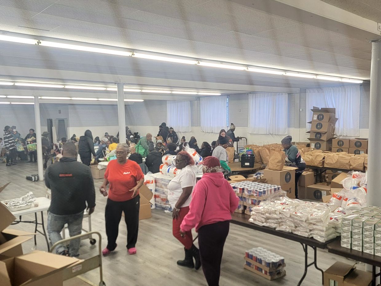 People gather in a large room for food distribution and community support.