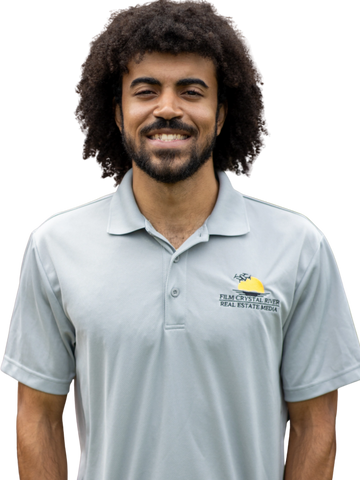 Smiling man in a gray polo shirt with a real estate logo.