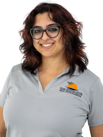 Woman with glasses wearing a gray polo shirt smiling.