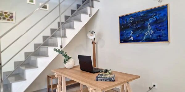 Office area featuring blue contemporary mixed media art piece with stairs to loft