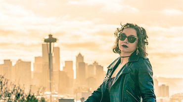 A woman in sunglasses poses at Kerry Park with the Seattle Space Needle in the background. 