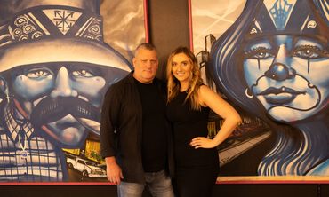A father and daughter pose in front of two large urban art pieces at Apex in Everett, Washington