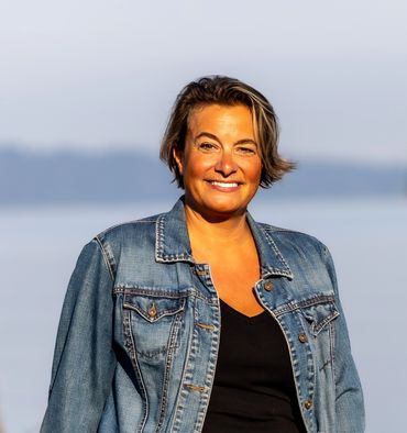 Woman smiling while standing at the waterfront.