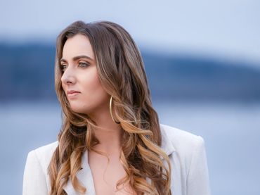 A woman standing near the waterfront looks into the distance.