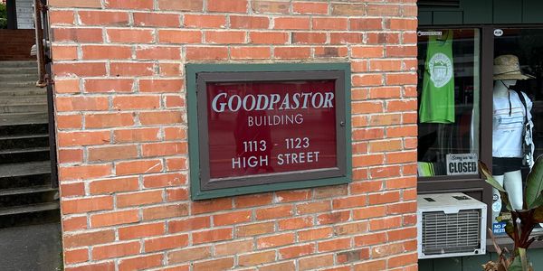 Sign for Goodpastor Building on a brick wall.