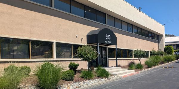 Office building exterior with plants and clear sky.
