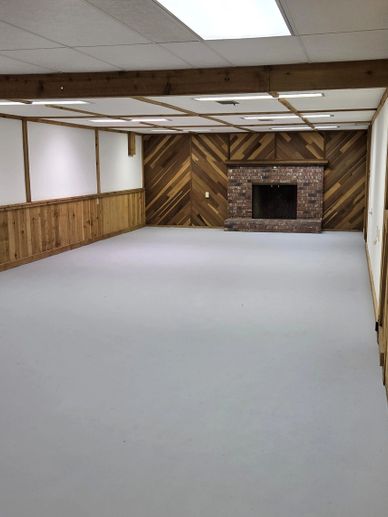 Empty room with wood-paneled walls and brick fireplace.