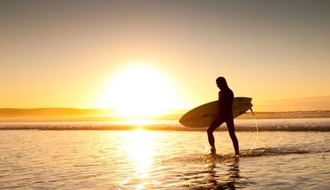 Surfer on a Cornish beach photographed against the sunset by Simon White Photography