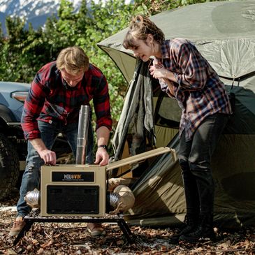 A couple camping with a heater to stay warm.
