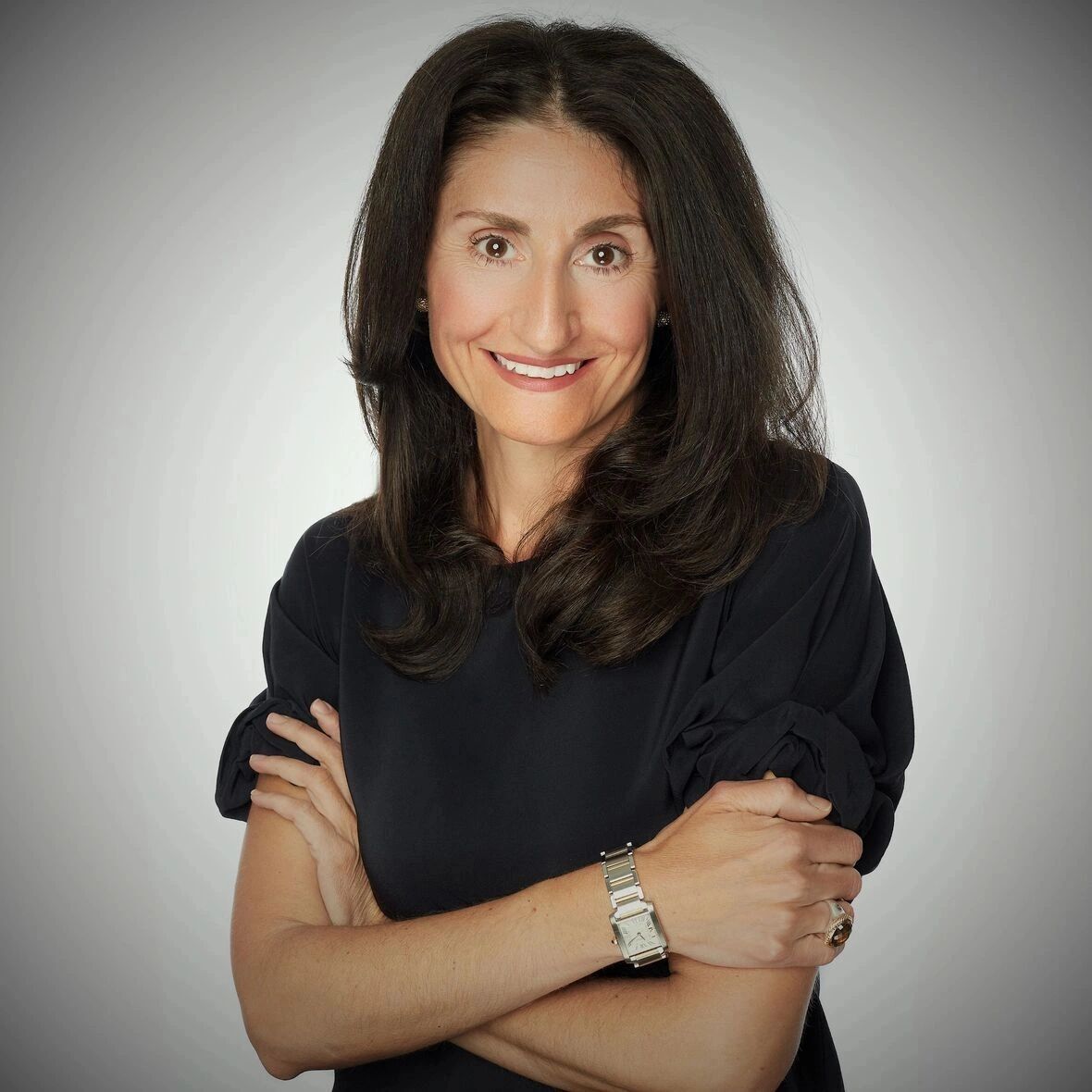 Confident woman with crossed arms and a warm smile.