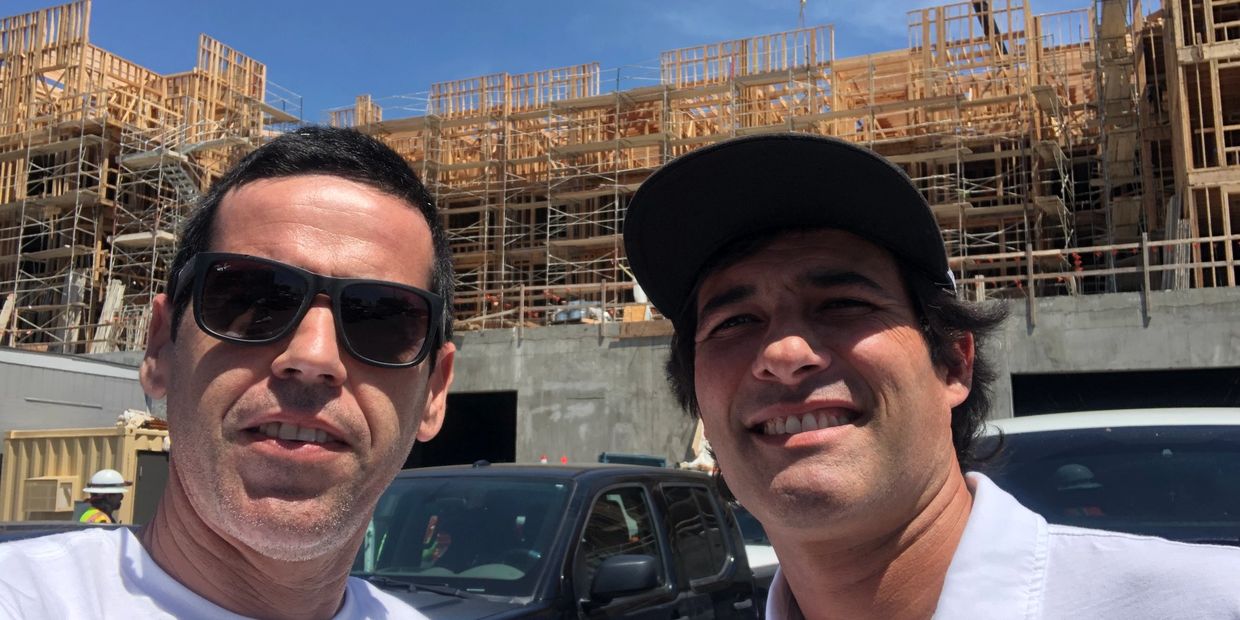 Two men taking a selfie in front of a construction site.