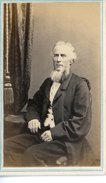 Historical photo of a bearded man sitting.