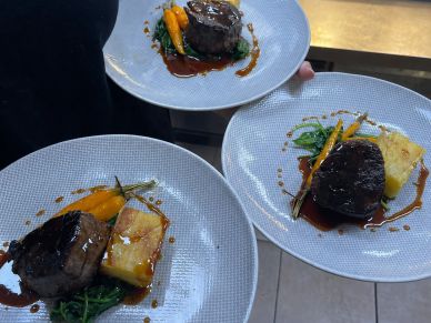 Three plates of gourmet steak with vegetables and sauce.