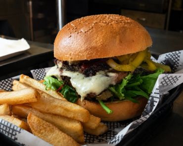 A cheeseburger with lettuce and peppers served with thick-cut fries.