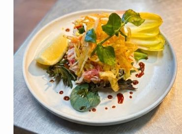 Samon rillete with gourmet salad with greens, lemon wedge, and crispy toppings on a white plate.