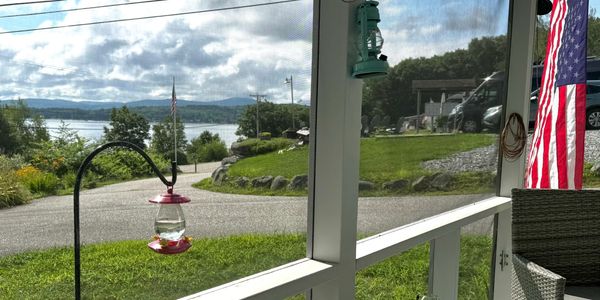 View from a screened porch overlooking a lake and garden.