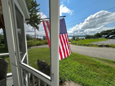 American flag hanging outside a porch on a sunny day.