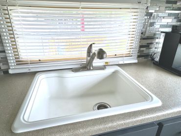 Clean white kitchen sink under window.