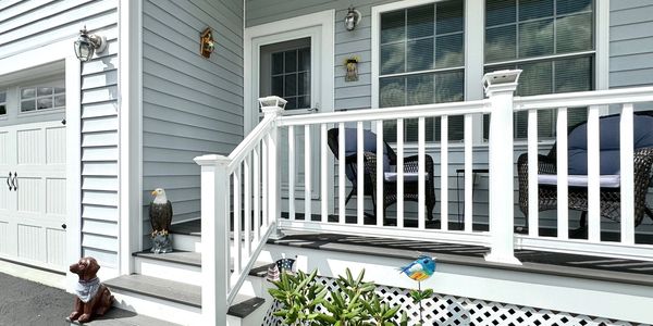 Front porch with white railing and garden decorations.