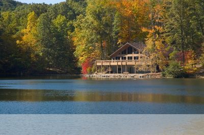 A house by a lake surrounded by autumn trees.